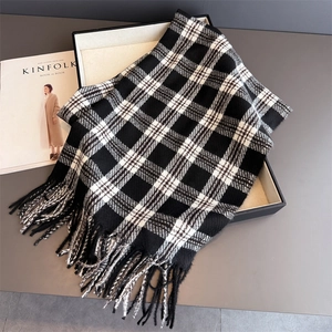 Gros plan d'une écharpe à carreaux noirs et blancs avec franges dans un coffret cadeau