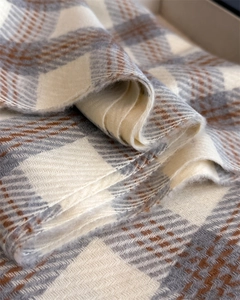 Détail d'une écharpe à carreaux beige et gris montrant le tissage doux en sergé
