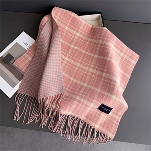 Close-up of pink and cream plaid scarf with houndstooth pattern and tassel details