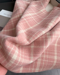 Close-up of pink and white plaid cashmere scarf with soft texture and fringe details