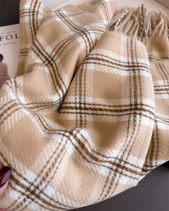 Gros plan sur la texture épaisse en cachemire beige à carreaux avec franges
