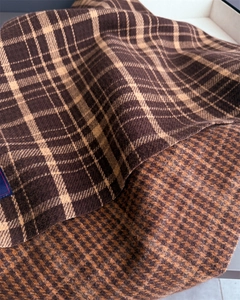 Detail showing the reversible plaid and houndstooth texture of the cashmere-like scarf