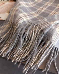 Gros plan du motif à carreaux gris et marron et texture douce des franges sur l'écharpe