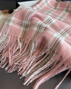 Gros plan d'une écharpe douce à carreaux rose et blanc avec franges et texture tissée