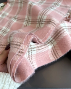 Gros plan sur l'écharpe en cachemire à carreaux rose et blanc avec détails de franges