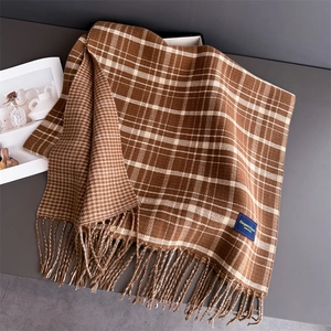 Detail of soft earth tone scarf featuring double-sided plaid and tassel fringe edges