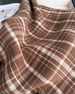 Close-up of brown and beige plaid cashmere scarf showing soft fringe and twill texture