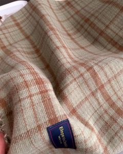 Detail of sage green and rust red plaid scarf fabric with elegant brand label