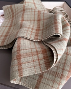 Close-up of grey-green and orange plaid scarf showing soft texture and fringe details