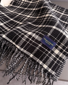 Close-up of black and white plaid cashmere scarf texture with fringe and woven label
