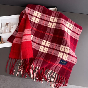 Detailed view of dark red plaid cashmere-textured scarf with fringe on a gray table