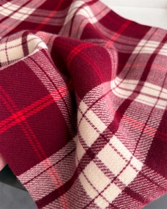 Close-up of red and white plaid cashmere scarf fabric showing soft fringe and fine weave