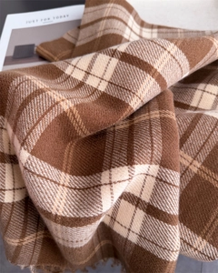 Detail of soft brown plaid scarf with fringe edge and warm knitted texture