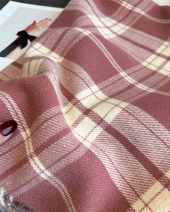 Close-up of pink plaid cashmere scarf showing herringbone texture and fringe details