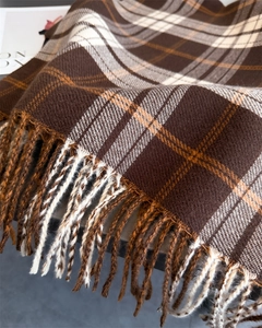 Detailed view of dark brown and beige plaid cashmere scarf featuring thick fringe trim