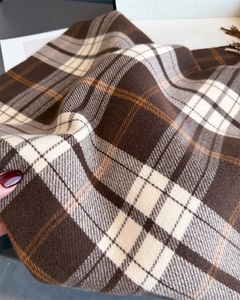 Close-up of soft brown plaid scarf texture showing fine cashmere feel and fringe detail