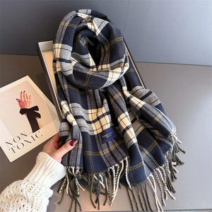 Close-up of classic navy blue plaid shawl with long tassels and soft knit texture