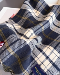 Macro shot of checkered cashmere feel scarf with navy green pattern and woven brand label
