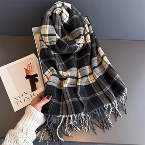 Detail of black and white plaid scarf with fringe tassels and soft cashmere texture