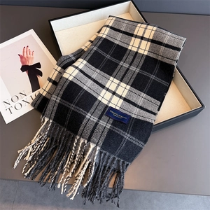 Close-up of black and white checkered scarf with soft fringe and elegant classic label