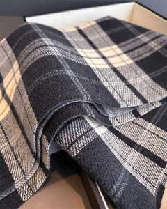Close-up of black and grey plaid scarf showing soft cashmere-like texture and tassels