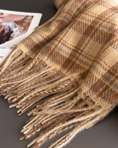 Detail of elegant beige plaid cashmere scarf featuring thick tassels and soft wool texture