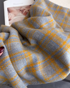 Close-up of thick plaid scarf texture with blue and orange tartan weave and tassels