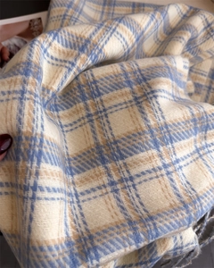 Close-up of soft blue and beige plaid scarf texture with delicate fringe edge details