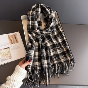 Close-up of classic plaid cashmere-like scarf with fine tassel details in a tray