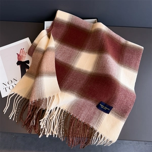 Close-up of elegant plaid scarf with soft tassels and branded woven label in a gift box