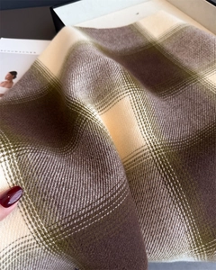 Macro shot of plaid scarf showing detailed weave texture and soft cashmere-like finish