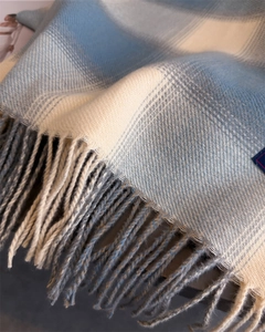 Detailed macro shot of soft plaid cashmere scarf with light blue and beige tassels