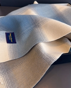 Macro detail of sky blue and grey plaid scarf fabric with elegant brand woven label