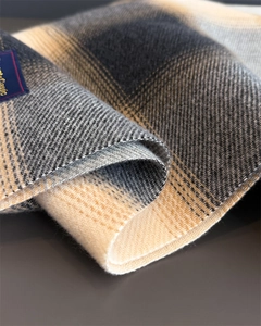 Close-up of black and beige plaid scarf showing soft twill weave and woven brand label