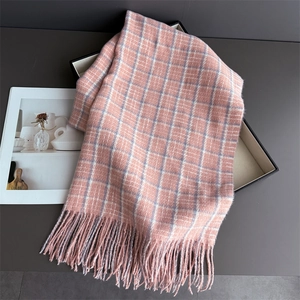 Close-up of pink and grey plaid scarf with soft fringe detail on a dark surface