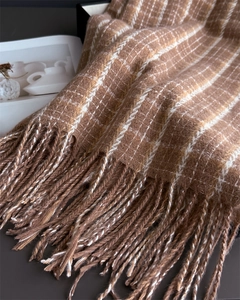 Close-up of brown plaid scarf with thick fringe detail and soft woven texture