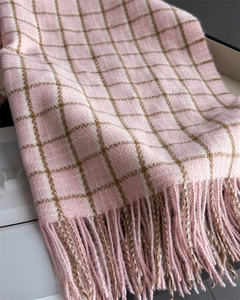 Macro shot of pink and white plaid knit scarf with soft texture and handmade long tassels