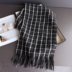 Detail shot of classic black and white plaid knit scarf featuring fringe tassels on the edge