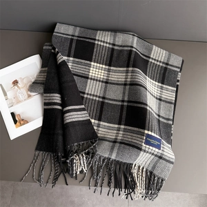 Detail of elegant black and white plaid scarf with soft fringe and stylish brand label