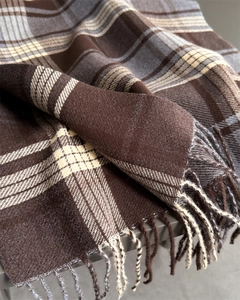 Detailed view of thick plaid cashmere-like scarf with dense fringe and soft knit texture