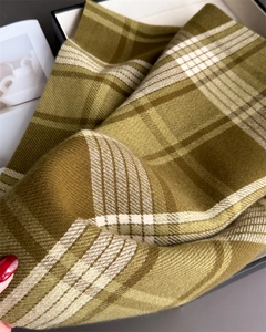 Macro view of olive green plaid cashmere scarf with classic fringe and twill weave