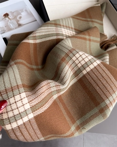 Close-up of soft plaid scarf showing brown and beige fringes and cashmere-like texture