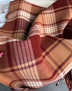 Close-up of soft plaid scarf with fringe detail in warm brown and orange tones