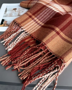 Detail of plaid scarf texture with orange and brown fringe tassels and soft fabric
