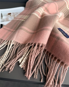 Detail of soft plaid scarf showing pink and beige weave with fringe and brand label