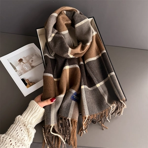 Detail of soft plaid scarf with tassels and brand tag on premium gift packaging