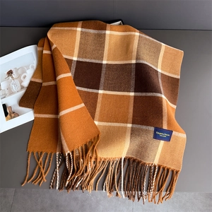 Macro detail of plaid cashmere-like scarf with soft tassels and woven brand label