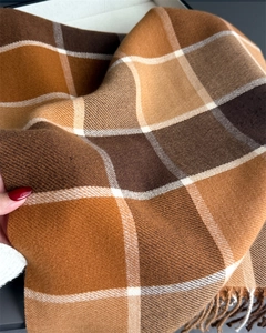 Close-up of soft brown plaid scarf texture showing fringe detail and weave pattern