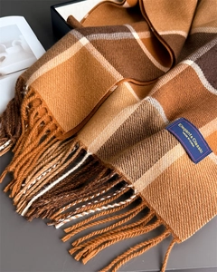 Close-up of classic brown plaid scarf with fringe detail and elegant woven label