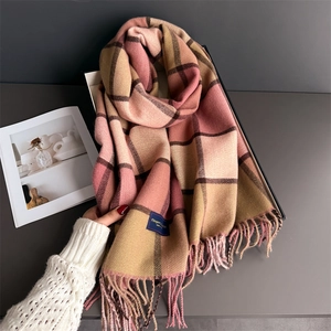 Close-up of pink and beige plaid scarf with soft fringe tassels and woven brand label